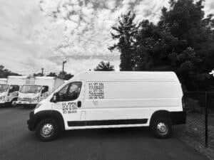 Transit cargo van in front of box trucks in parking lot